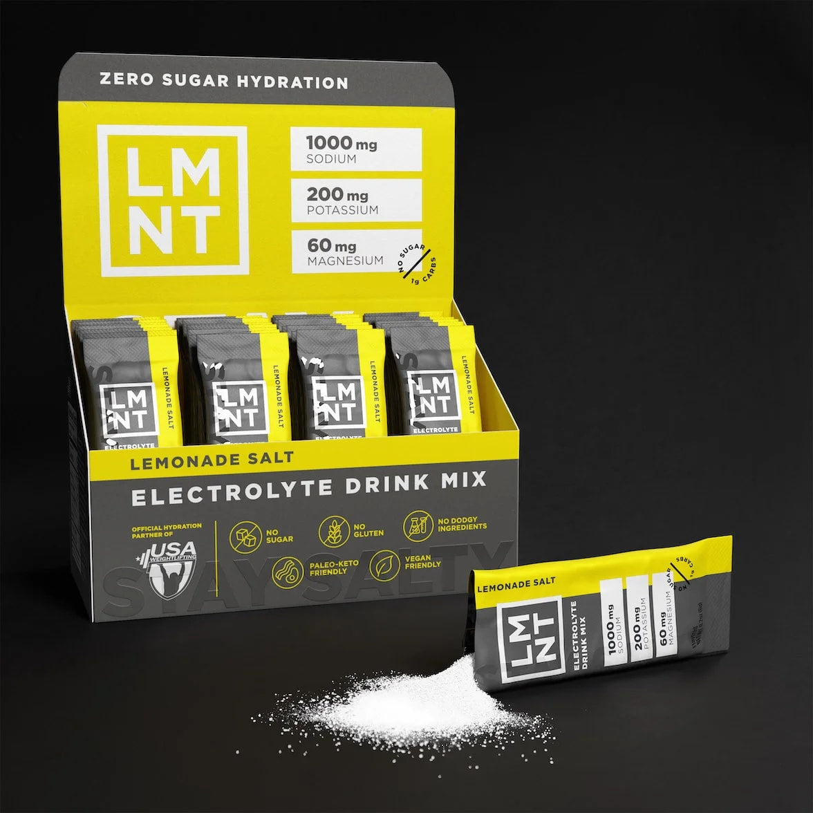 Open box of LMNT Lemonade Salt electrolyte drink mix with stick packs and one sachet beside a pile of powder.