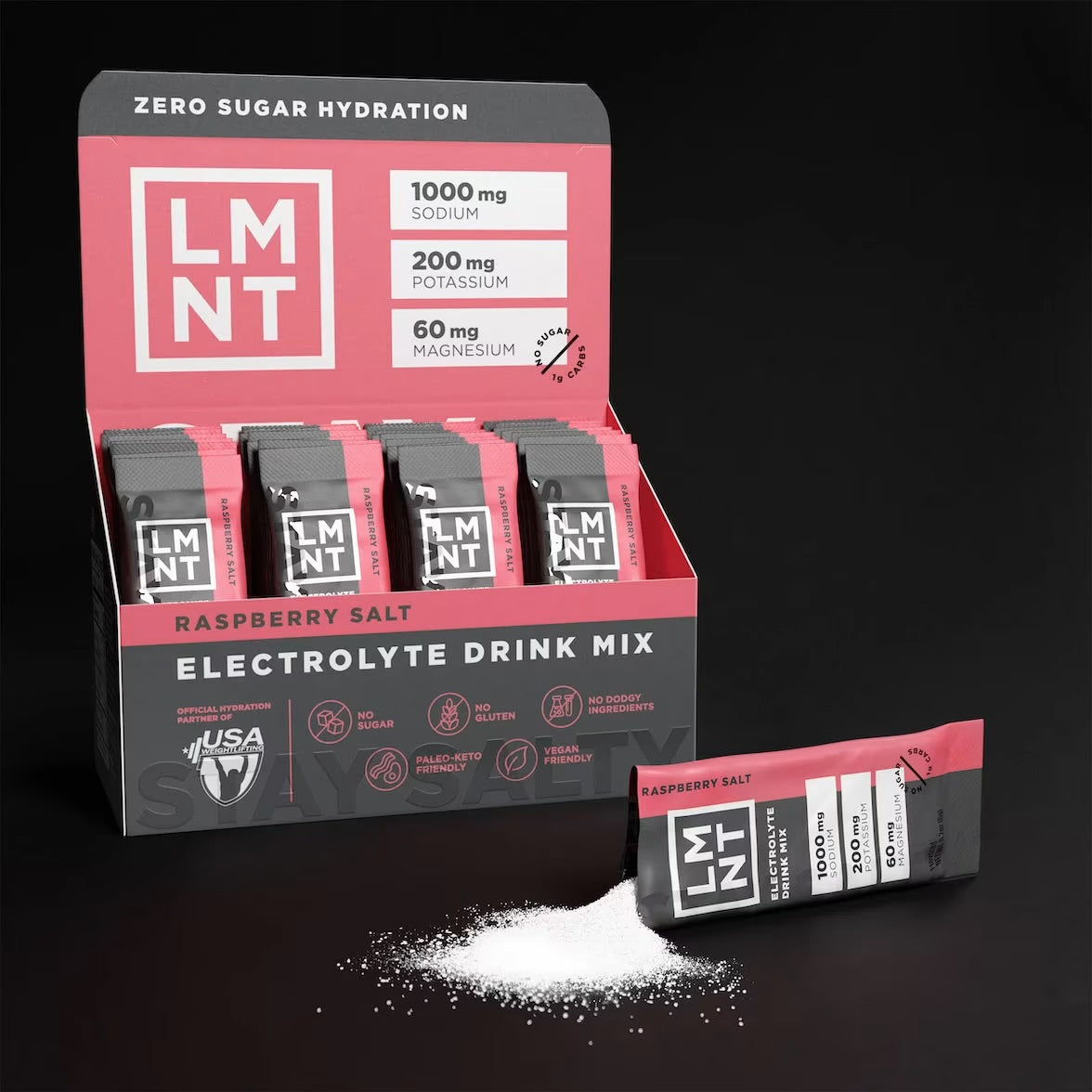 Open box of LMNT Raspberry Salt electrolyte drink mix with individual sachets and a sachet beside a pile of powder.